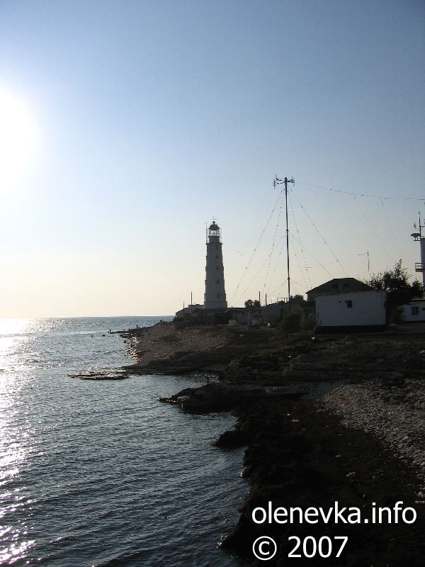 Маяк с берега моря в лучах заходящего солнца, маяк Оленевки